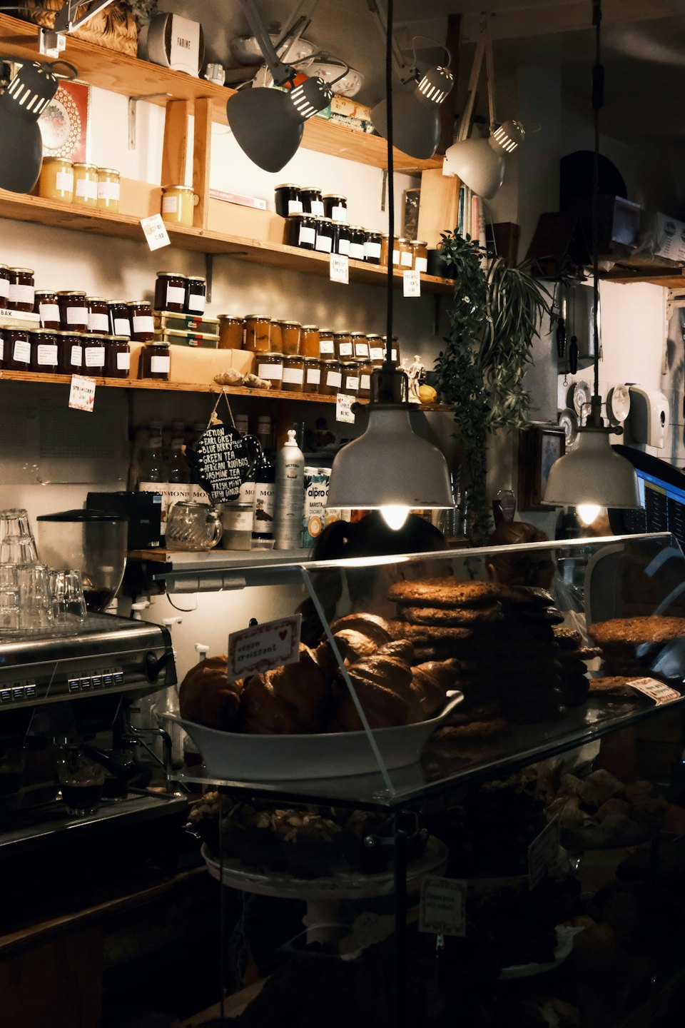 Pastane tezgahı reçel kavanozları ve espresso makinesiyle dolu.